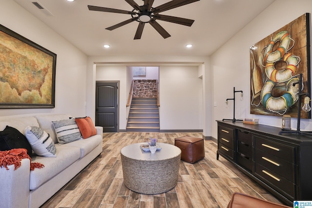 living area featuring ceiling fan, stairs, visible vents, and wood finish floors