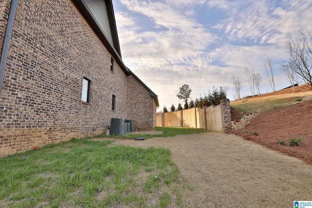 view of property exterior featuring brick siding and fence