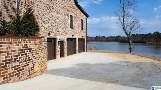 view of patio featuring a garage, driveway, and a water view