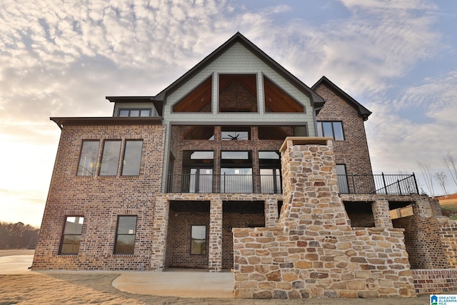 view of front facade with brick siding and a balcony