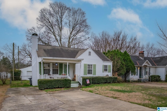 view of front facade featuring a garage, a front yard, covered porch, and a chimney