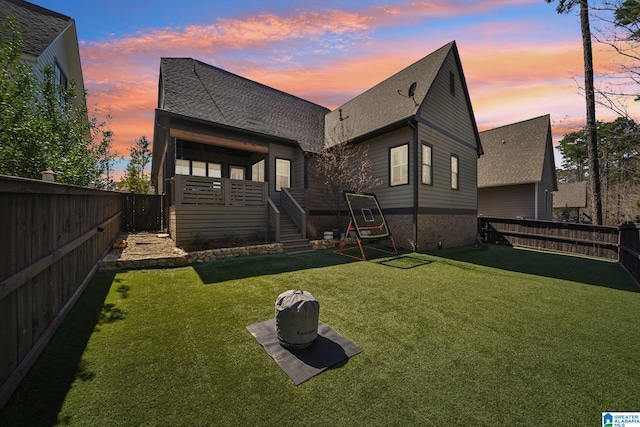 51 Nolen St, Birmingham, AL 35242 - back of property at dusk with a fenced backyard, stairs, a shingled roof, and a lawn