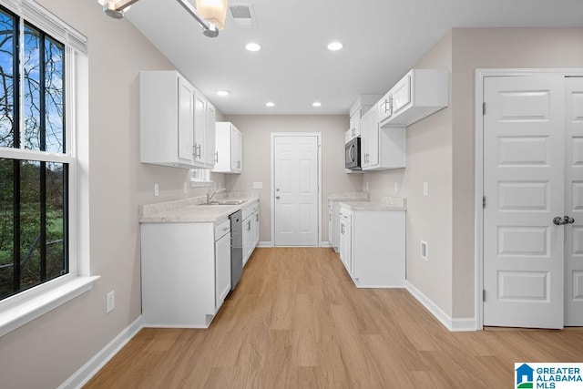 kitchen with stainless steel appliances, visible vents, white cabinets, and light wood-style flooring