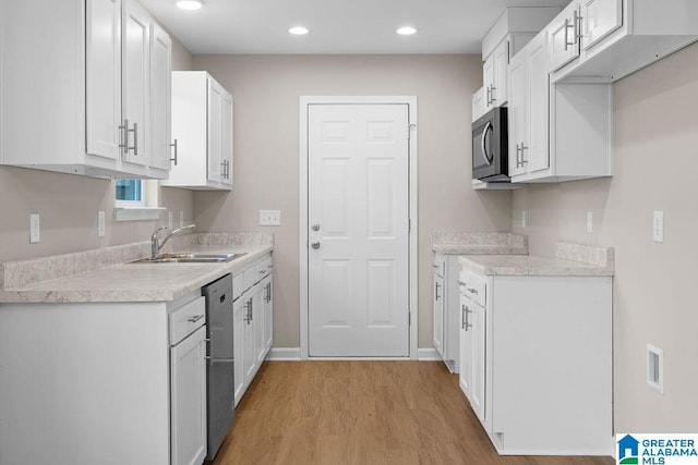 kitchen featuring light countertops, light wood-type flooring, a sink, and white cabinets