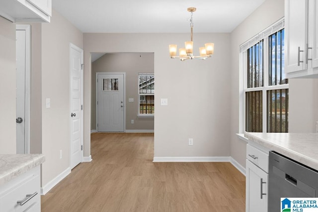 unfurnished dining area featuring light wood-type flooring, baseboards, and an inviting chandelier