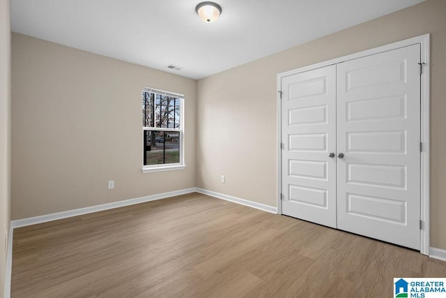 unfurnished bedroom with light wood finished floors, visible vents, baseboards, and a closet