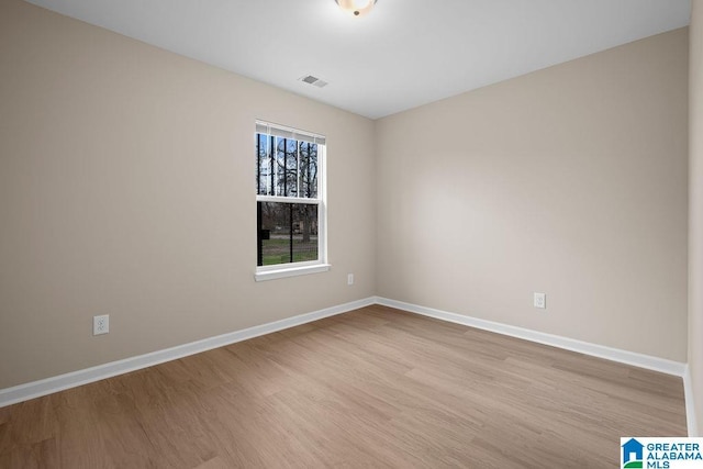 empty room featuring visible vents, light wood-style flooring, and baseboards