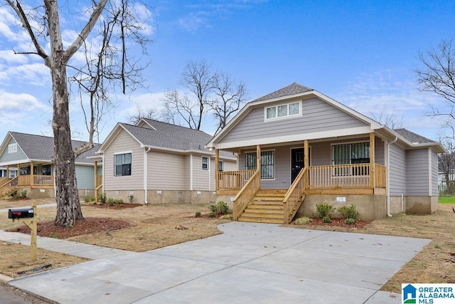 bungalow-style home with covered porch, roof with shingles, stairway, and crawl space