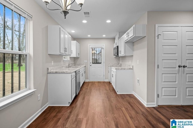 kitchen with light stone countertops, stainless steel appliances, visible vents, and white cabinets