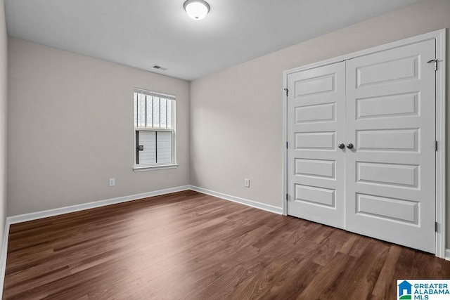 unfurnished room featuring dark wood-type flooring, visible vents, and baseboards