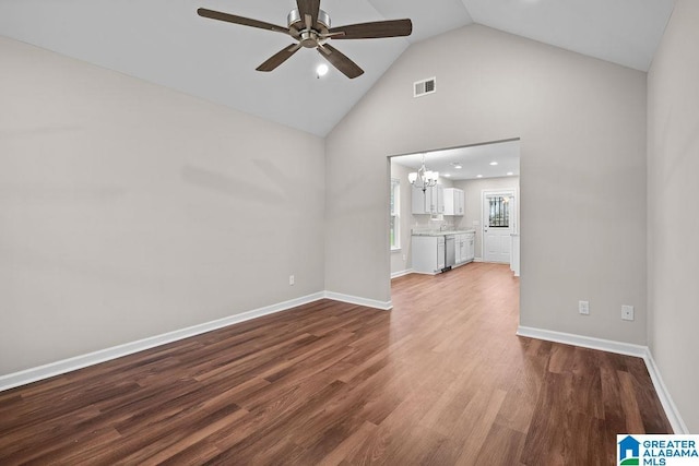 unfurnished living room with high vaulted ceiling, ceiling fan with notable chandelier, baseboards, and wood finished floors