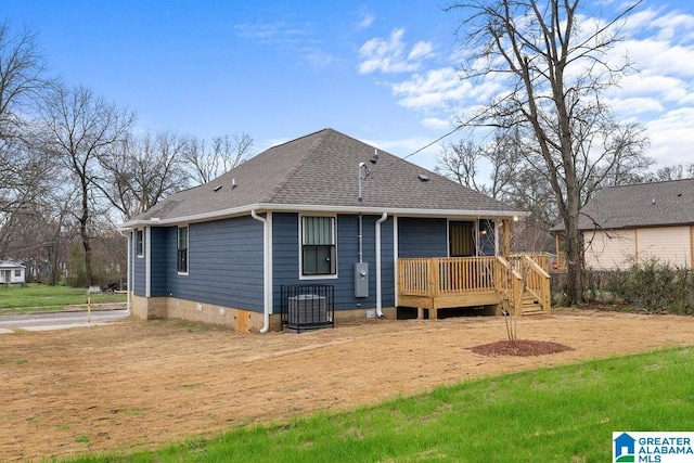 rear view of property with a shingled roof and a wooden deck