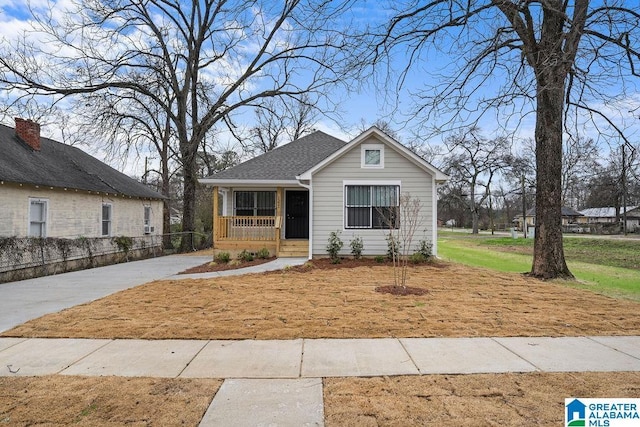 bungalow-style house featuring covered porch, a front lawn, and roof with shingles