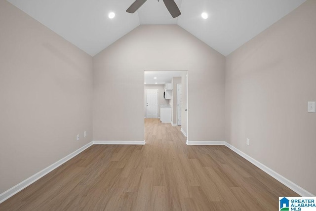 spare room featuring light wood-style floors, lofted ceiling, baseboards, and a ceiling fan