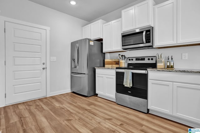 kitchen featuring white cabinets, light stone countertops, light wood-type flooring, and stainless steel appliances