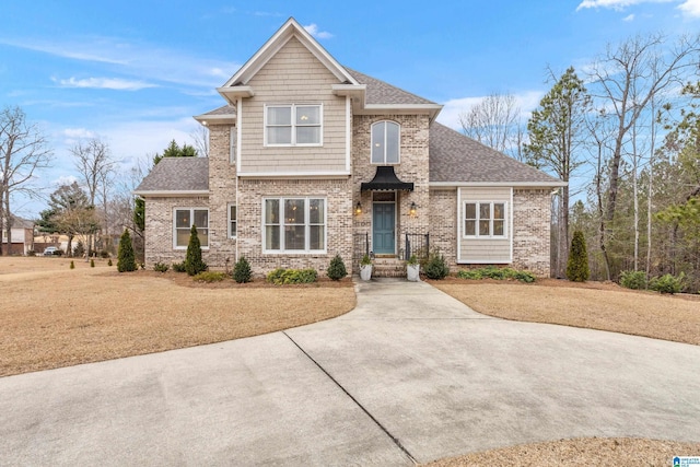 craftsman-style home featuring a shingled roof, brick siding, and a front lawn