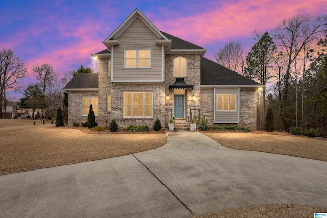 view of front of house with brick siding and roof with shingles