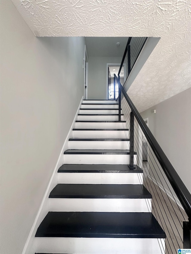 stairs featuring a textured ceiling