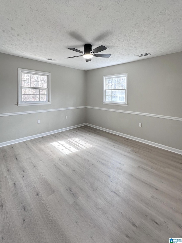 spare room with visible vents, baseboards, and wood finished floors