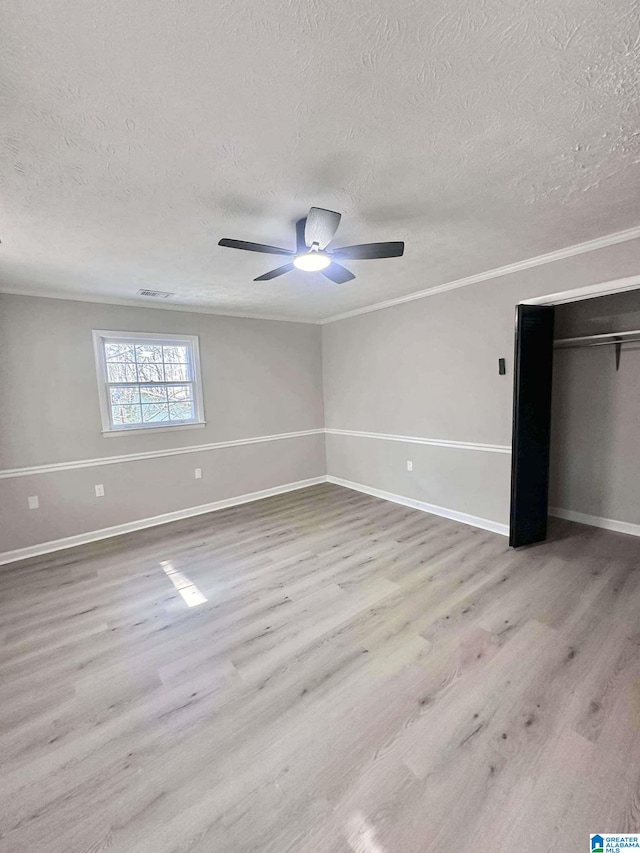 unfurnished bedroom with ceiling fan, a textured ceiling, wood finished floors, baseboards, and ornamental molding