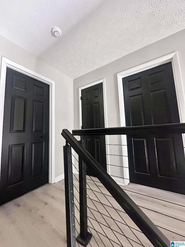 foyer featuring light carpet, baseboards, and a textured ceiling