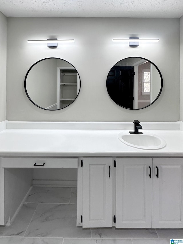 bathroom with marble finish floor, a textured ceiling, and vanity