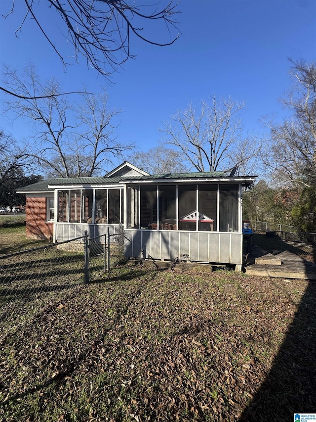 back of property featuring a sunroom and fence