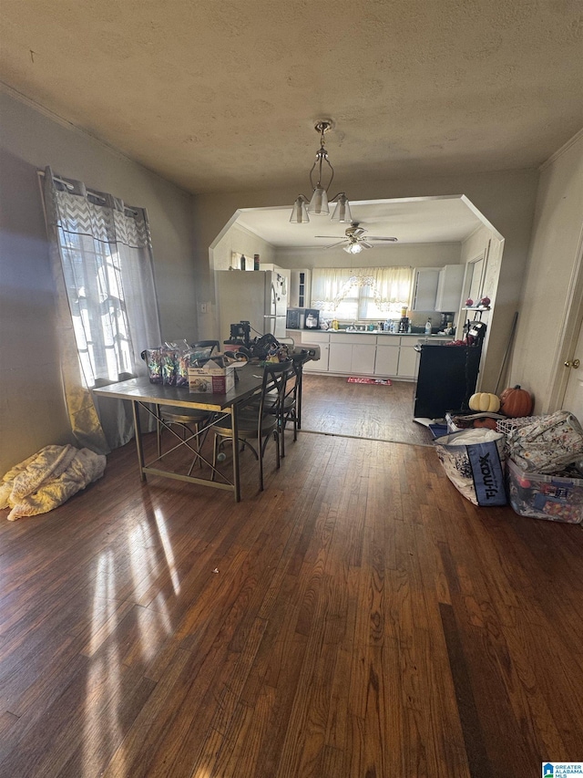 dining space featuring a textured ceiling, dark wood-style flooring, and a ceiling fan