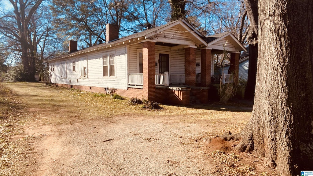 view of side of property with crawl space, a chimney, and a porch