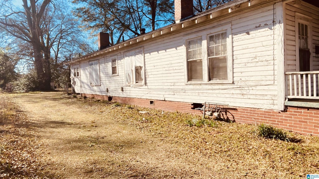 view of property exterior featuring crawl space and a chimney