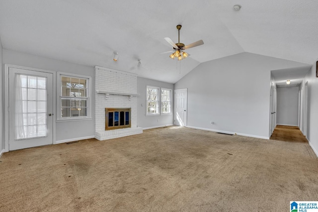 unfurnished living room featuring lofted ceiling, a ceiling fan, a brick fireplace, carpet flooring, and baseboards