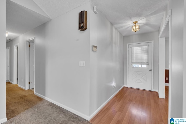 foyer entrance featuring a textured ceiling, light wood-type flooring, and baseboards