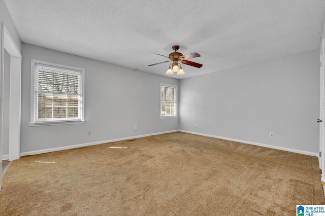 carpeted spare room featuring a textured ceiling, a ceiling fan, and baseboards