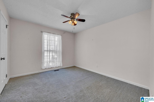 carpeted empty room featuring ceiling fan, visible vents, baseboards, and a textured ceiling