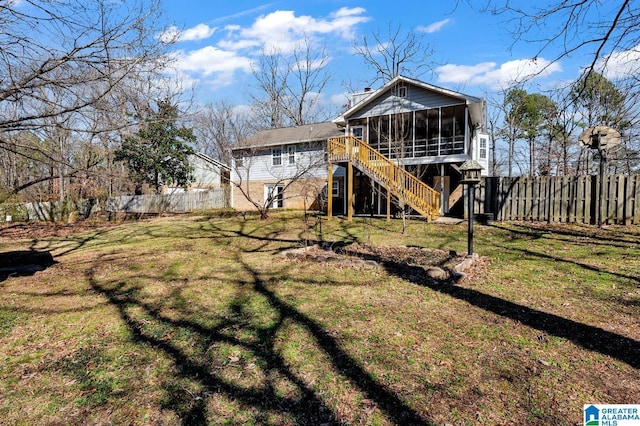 rear view of house with a fenced backyard, a sunroom, a yard, stairway, and a chimney