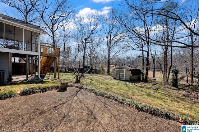 view of yard with an outbuilding, a deck, a sunroom, stairs, and a shed