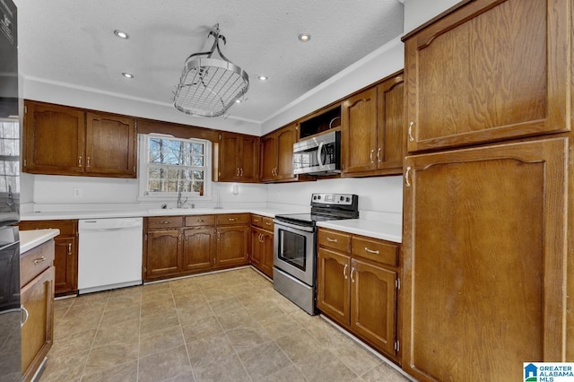 kitchen with brown cabinets, stainless steel appliances, a textured ceiling, light countertops, and recessed lighting