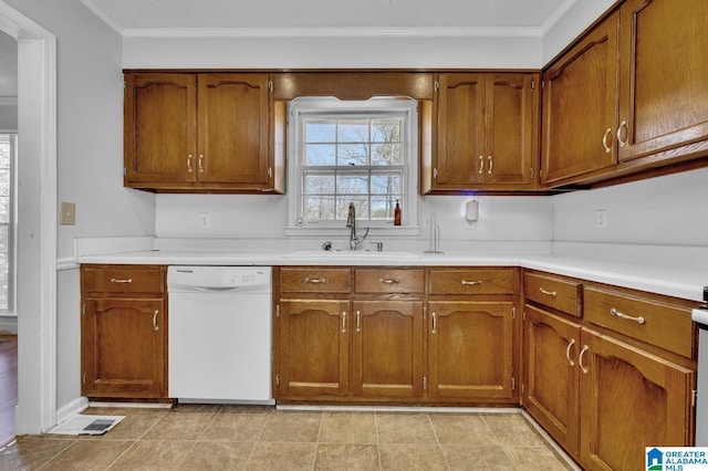 kitchen with brown cabinetry, light countertops, white dishwasher, and a sink