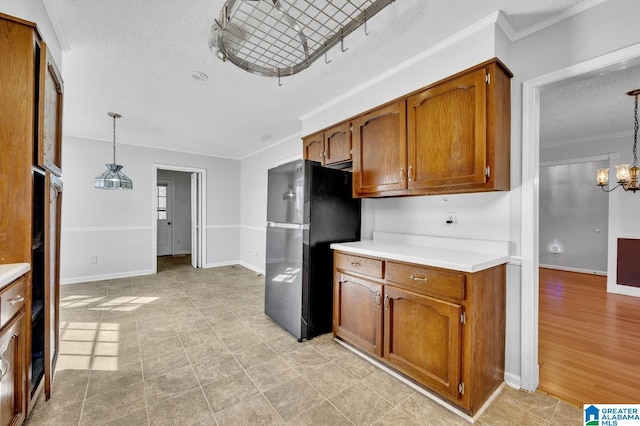 kitchen featuring brown cabinetry, freestanding refrigerator, pendant lighting, and light countertops