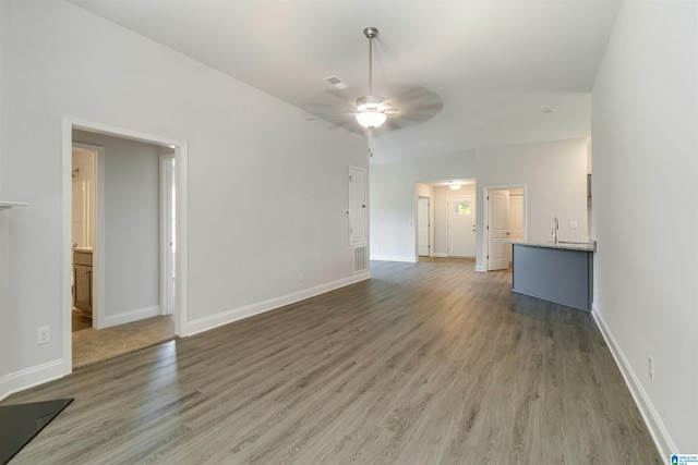 unfurnished living room with ceiling fan, wood finished floors, visible vents, and baseboards