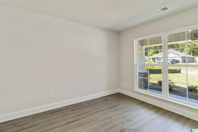 unfurnished room with plenty of natural light, visible vents, baseboards, and dark wood finished floors