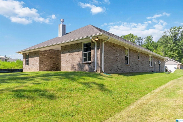 view of side of home featuring a chimney, a lawn, and brick siding