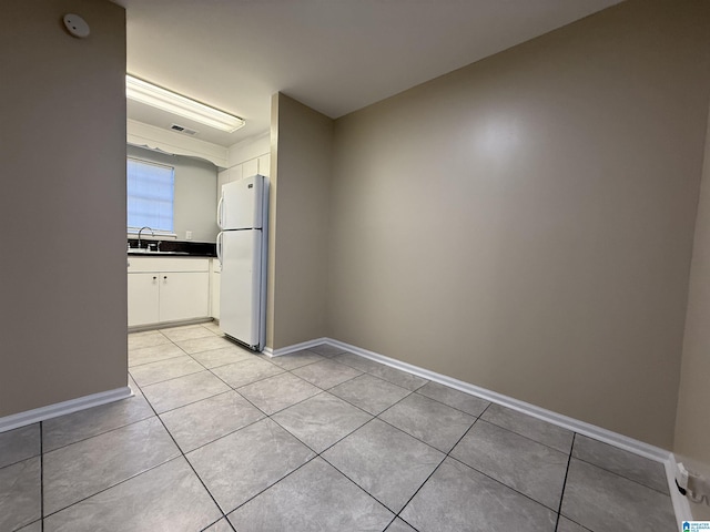 interior space featuring light tile patterned flooring, a sink, visible vents, and baseboards