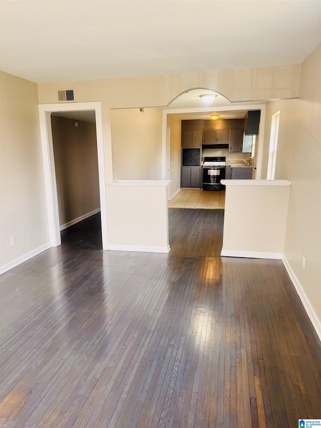 unfurnished living room featuring dark wood-style floors, baseboards, and visible vents