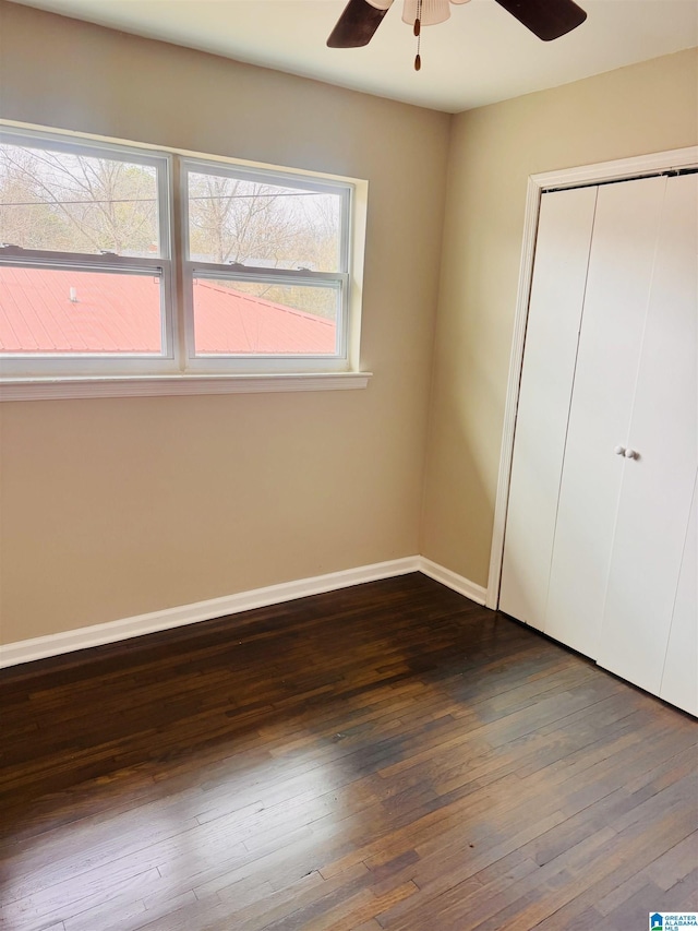 unfurnished bedroom with ceiling fan, baseboards, dark wood finished floors, and a closet