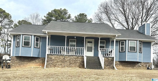 view of front facade with a chimney, a porch, and a front yard