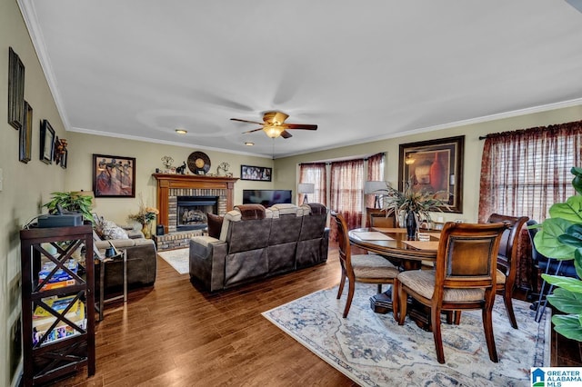 dining room with a fireplace, wood finished floors, a ceiling fan, and crown molding