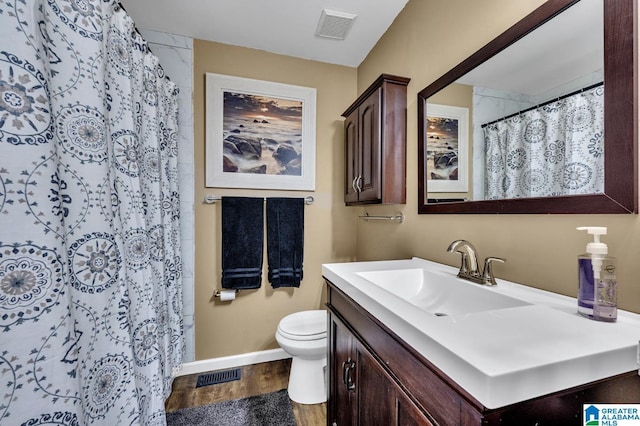 bathroom with visible vents, a shower with shower curtain, toilet, vanity, and wood finished floors