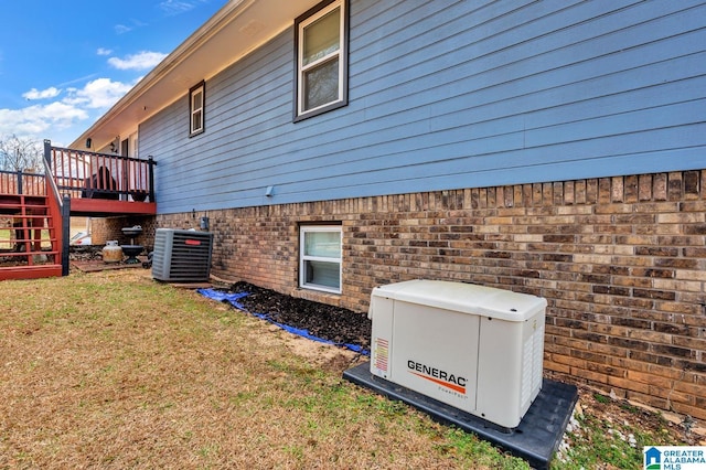 view of side of property with brick siding, a yard, central air condition unit, stairway, and a wooden deck