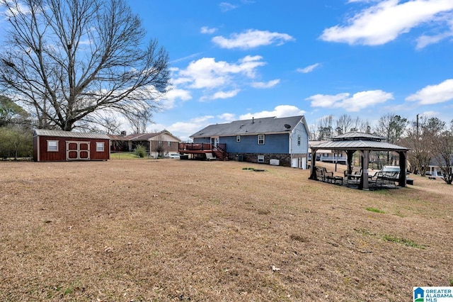 view of yard featuring an outbuilding, a wooden deck, a gazebo, and a shed